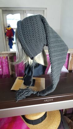 a mannequin's head wearing a gray knitted hat and scarf on top of a table