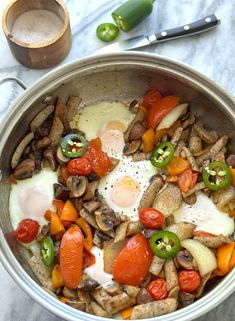 a pan filled with eggs, tomatoes and mushrooms