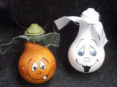 two painted pumpkins sitting next to each other on a black surface with a white ribbon