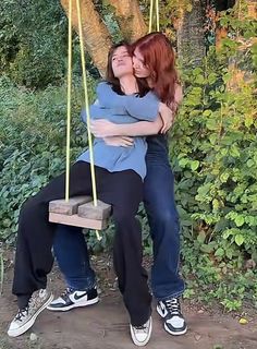 two women hugging each other on a swing