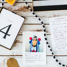 a table topped with pictures and cards on top of a white wooden floor next to other items