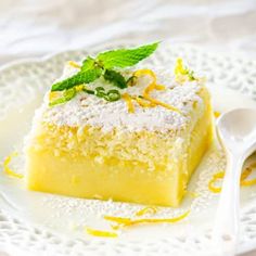 a white plate topped with a piece of cake covered in powdered sugar and mint