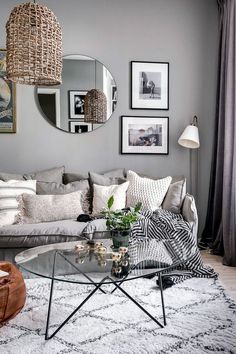 a living room filled with furniture and pictures hanging on the wall above a glass coffee table