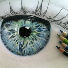 a drawing of an eye with colored pencils in front of it and the caption below