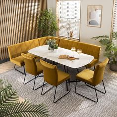 a dining room table with yellow chairs and a plant in the corner next to it