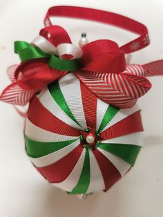 a christmas ornament with red, green and white ribbons on it's side