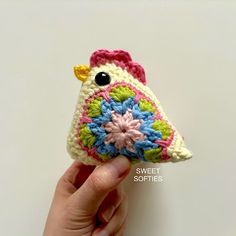 a small crocheted bird is held up by someone's hand