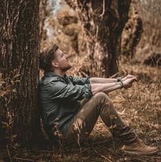 a man sitting under a tree in the woods