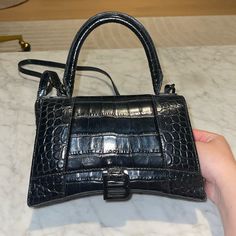 Black On Black Croc Embossed Balenciaga Hourglass Bag Dimensions: L9 X H5.5 X W3.9 Inch Worn With Love But Ready To Go To A New Home Still In Pretty Good Condition Despite How Much It’s Been Worn Some Wear And Tear On The Handle Part And On The Inside Also But A Little Clean Up Can Make It Look New In No Time. Overall Look It Still Looks Like Amazing Condition Black Handheld Satchel With Branded Hardware, Black Square Satchel For Evening, Modern Black Satchel For Party, Designer Black Square Satchel, Designer Black Satchel For Evening, Classic Black Satchel For Party, Luxury Black Satchel For Party, Black Shoulder Bag With Branded Hardware For Party, Designer Black Satchel For Party