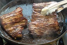 two steaks being cooked in a skillet with chopsticks sticking out of them