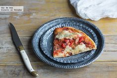 a slice of pizza on a black plate next to a knife and napkin with tissue paper