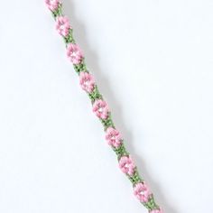 a pink and green braided ribbon on a white surface