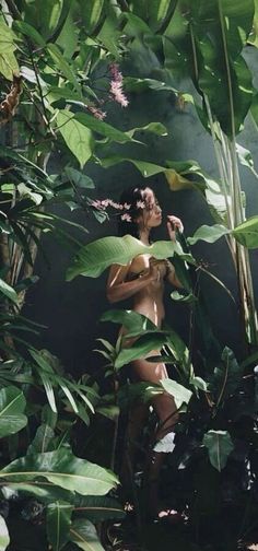 a naked woman standing in the jungle surrounded by plants