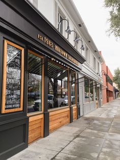 an empty sidewalk in front of a restaurant with wood trimmings on the windows