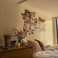 a bedroom with pictures on the wall and flowers in a vase next to a bed