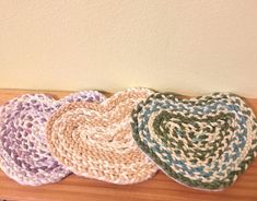 four crocheted hats sitting on top of a wooden table next to a wall