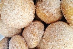 a pile of sugared donuts sitting on top of a white tablecloth covered plate