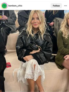 a woman sitting on top of a white couch next to another woman in black jacket