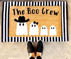 a person standing in front of a door mat that says the boo crew