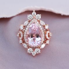 a pink diamond ring sitting on top of a white cloth