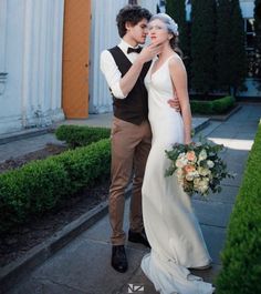 a bride and groom standing in front of a building