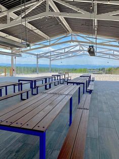 several wooden benches are lined up under a roof