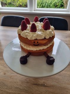 a cake sitting on top of a white plate covered in whipped cream and strawberries