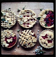 four pies are arranged on a table with flowers and leaves in the middle,