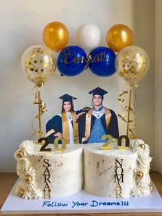 a cake with two graduates and balloons on it