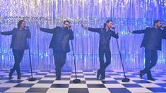 the backs perform on stage in front of a checkerboard floor and blue curtain