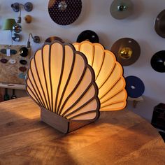 two lamps sitting on top of a wooden table in front of a wall filled with plates