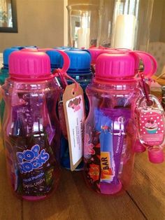 four plastic bottles with tags on them sitting on a wooden table next to each other