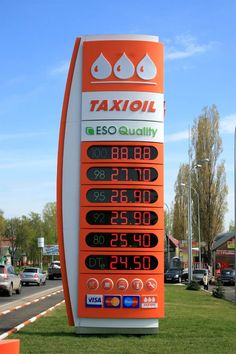 an orange and white gas station sign in the grass