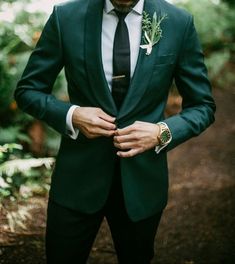 a man in a suit and tie is looking down at his hand on his lapel