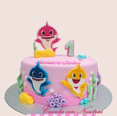 a pink birthday cake decorated with cartoon shark and other sea creatures, including a number one