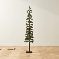 a small pine tree is plugged in to an electrical outlet on the wooden floor