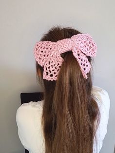 a woman with long hair wearing a pink crochet bow