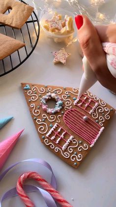 someone is decorating a gingerbread house with icing