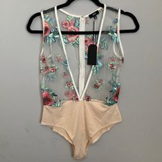 a women's bodysuit hanging on a hanger in front of a gray wall