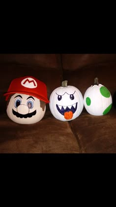 three pumpkins painted to look like mario and luigi's faces on a couch