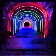 a white couch sitting under a tunnel filled with neon colored lights in a dark room