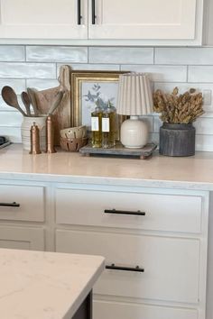 a kitchen counter with white cabinets and gold accessories on it, including an old clock