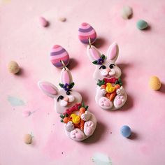 two bunny shaped earrings sitting on top of a pink surface