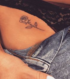 a woman's stomach with a rose tattoo on her left side ribcage