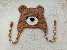 a crocheted brown bear hat on top of a white blanket