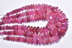 pink tourmaline beads are lined up on a white surface