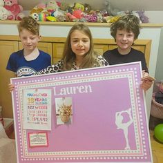 three children holding up a large pink poster