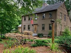 an old house with a wagon in front of it and trees around the yard area