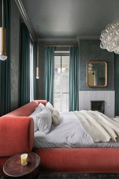 a bedroom with green curtains and a red bed in the middle, along with a fireplace