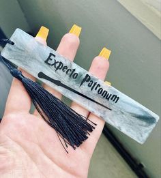 a hand holding an object that says expect protrunin on it with tassels